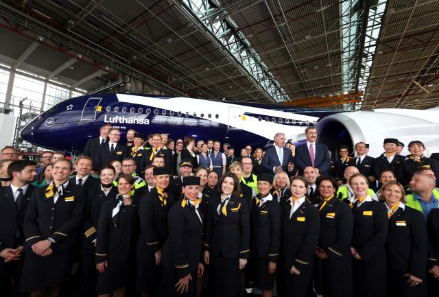 23 March 2026, Bavaria, Munich: Markus Soeder (top right), Bavarian Minister President and Carsten Spohr, Chairman of the Executive Board of Deutsche Lufthansa, stand together with Lufthansa employees in front of the Airbus A350-900 Rostock on the occasion of Lufthansa's centenary celebrations. Photo: Karl-Josef Hildenbrand/dpa