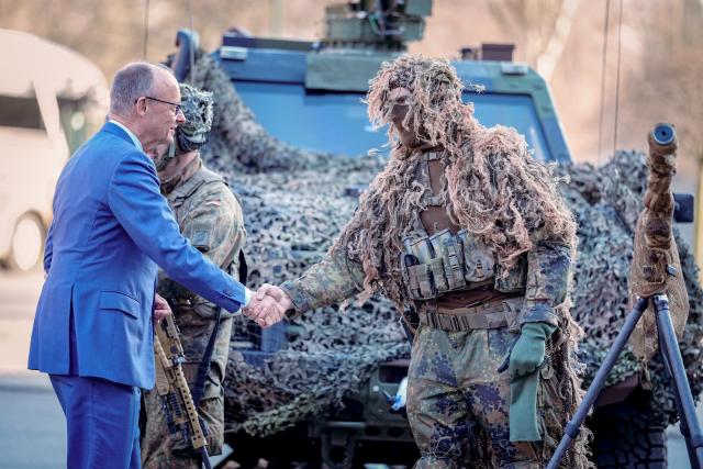 23 March 2026, Berlin: German Chancellor Friedrich Merz (L) is greeted by a sniper at the presentation of the flag ribbon to the guard battalion. Photo: Kay Nietfeld/dpa