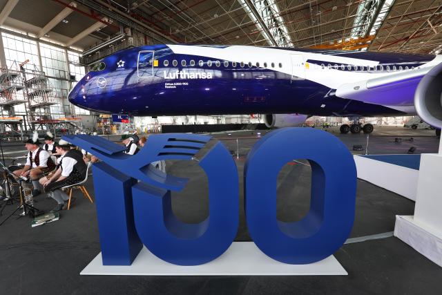 23 March 2026, Bavaria, Munich: The number 100 stands in front of the Airbus A350-900 Rostock during the celebration of Lufthansa's 100th anniversary. Photo: Karl-Josef Hildenbrand/dpa