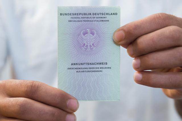 FILED - 25 May 2016, Saxony, Dresden: Iranian Mohammadi Nasir shows his certificate of arrival in Dresden. The escalation of the US-Israeli- Iranian conflict has sparked debate in Germany about the potential for refugee flows from the region, with a poll showing that a majority of citizens believe their country would be unable to cope well with the arrival of more refugees. Photo: Sebastian Kahnert/dpa-Zentralbild/dpa