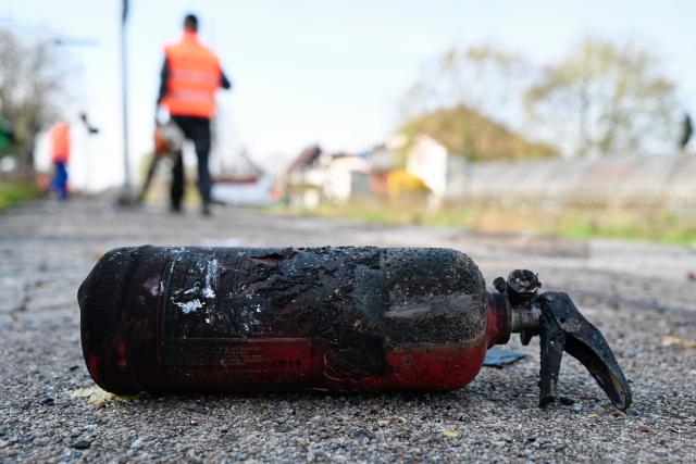 24 March 2026, Rhineland-Palatinate, Insheim: A Deutsche Bahn employee walks past a charred fire extinguisher on the station platform, where several people have been injured in a collision between a regional train and a car transporter in the Southern Palatinate. Photo: Uwe Anspach/dpa