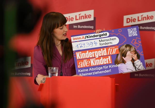 24 March 2026, Berlin: Heidi Reichinnek, leader of the Left party's parliamentary group, holds a poster on child benefit, as she give a statement before the parliamentary group meeting in the German Parliament (Bundestag). Photo: Lilli Förter/dpa