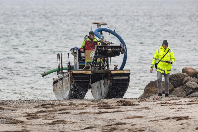 24 March 2026, Schleswig-Holstein, Timmendorf: A suction dredger is being used to create a passage for a whale stranded on the Baltic Sea coast near Niendorf. Biologists hope the animal will then be able to move into deeper water on its own. Police have cordoned off the area to avoid disturbing the whale. Photo: Ulrich Perrey/dpa