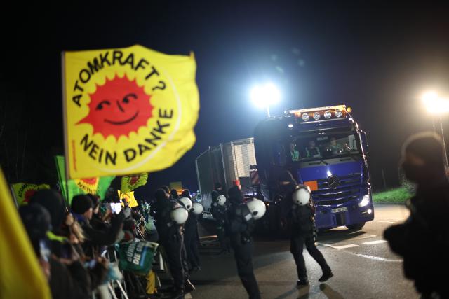 25 March 2026, North Rhine-Westphalia, Ahaus: A heavy goods vehicle carrying a Castor container drives past protestors during an anti-nuclear demonstration against the Castor transports along the route near Ahaus. Photo: Christoph Reichwein/dpa