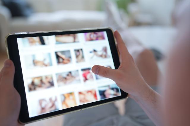FILED - 14 April 2025, Hamburg: A young person looks at a porn website on a smartphone. Four major pornographic platforms including Pornhub could face massive fines after they were found to be breaching EU law by allowing minors to access the sites, according to preliminary results of a European Commission investigation. Photo: Marcus Brandt/dpa