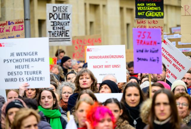 26 March 2026, Berlin: Participants in a rally organized by the Psychotherapy Action Alliance demonstrate outside the Germany's Ministry of Health against cuts to the fees of outpatient psychotherapists, holding signs reading, among other things, '4.5 percent cut: 100 percent miscalculated.' Photo: Soeren Stache/dpa
