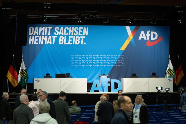 28 March 2026, Saxony, Loebau: Participants at the Alternative for Germany (AfD) Saxony state party convention stand in front of the stage at the Loebau Exhibition and Event Park. Photo: Sebastian Kahnert/dpa