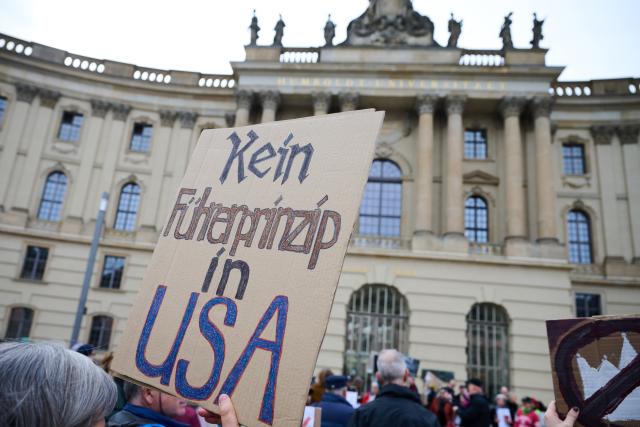 28 March 2026, Berlin: A protester holds a sign reading 'No leader principle in the U.S.' on Bebelplatz during a demonstration against the Trump administration. Protests against President Donald Trump's policies are taking place in Germany as well as in many US cities and other locations worldwide. Photo: Annette Riedl/dpa