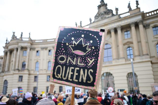 28 March 2026, Berlin: A protester holds a sign reading 'Only Queens' on Bebelplatz during a demonstration against the Trump administration. Protests against President Donald Trump's policies are taking place in Germany as well as in many US cities and other locations worldwide. Photo: Annette Riedl/dpa