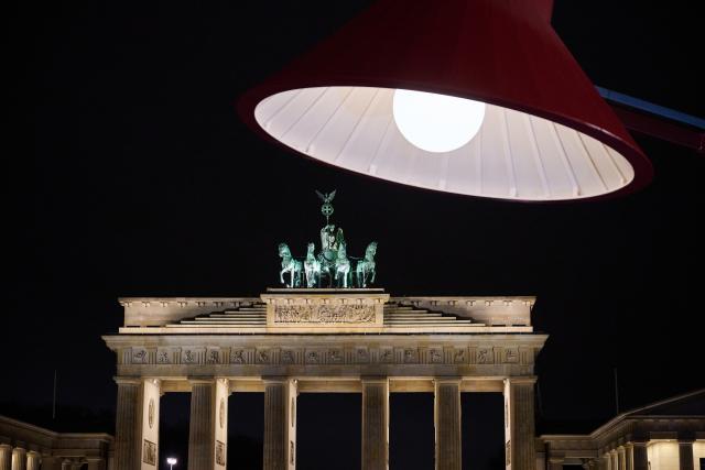 28 March 2026, Berlin: A giant lamp shines in front of the still-illuminated Brandenburg Gate ahead of Earth Hour. The global campaign, organized by the environmental group WWF, sees lights switched off for one hour from 20:30 local time to raise awareness of climate and environmental protection. Photo: Annette Riedl/dpa