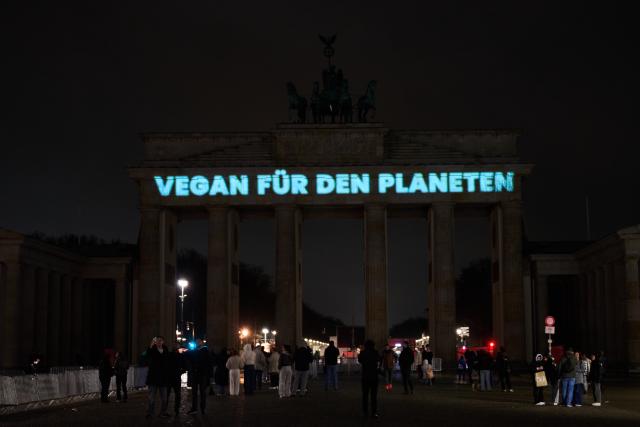28 March 2026, Berlin: The words 'Vegan for the Planet' are projected onto the darkened Brandenburg Gate during Earth Hour. The global campaign, organized by the environmental group WWF, sees lights switched off for one hour from 20:30 local time to raise awareness of climate and environmental protection. Photo: Annette Riedl/dpa
