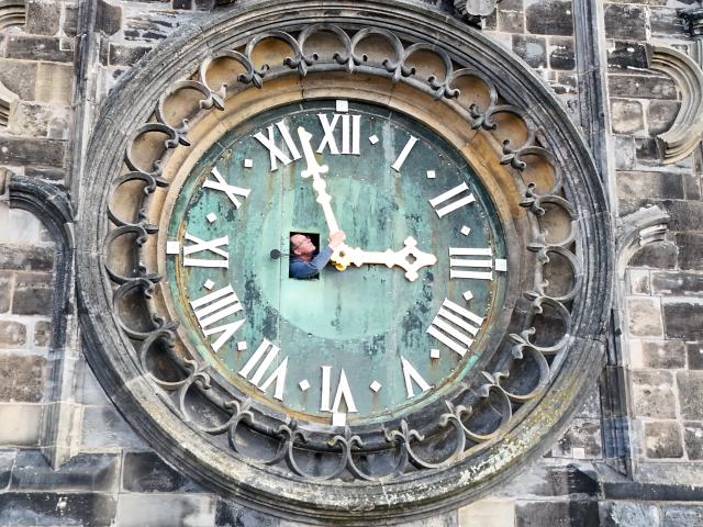 FILED - 20 March 2026, Saxony-Anhalt, Magdeburg: Hans Studte, sexton of Magdeburg Cathedral, checks the hands of the western tower clock through a hatch in a drone shot. The fully mechanical clock dates back to 1860. Clocks in Germany will be set forward by one hour next weekend as daylight saving time begins. Photo: Peter Gercke/dpa
