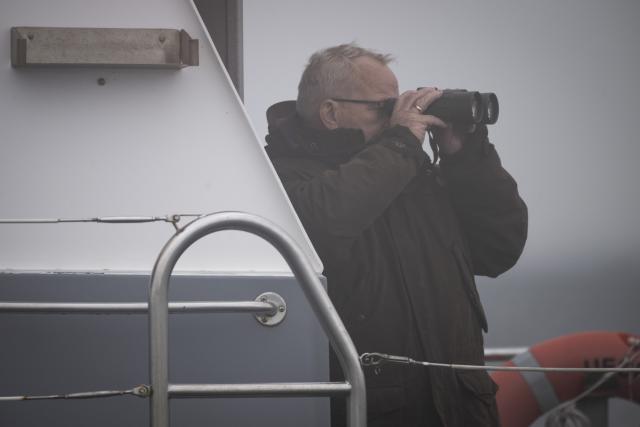 29 March 2026, Mecklenburg-Western Pomerania, Wismar: Mecklenburg-Western Pomerania's Minister President Till Backhaus  stands on the police boat "Uecker" with binoculars to monitor the sitiuation with the stranded whale. The humpback whale, which had been freed off Timmendorfer Strand, has stranded again on a sandbar in Wismar Bay. Photo: Philip Dulian/dpa