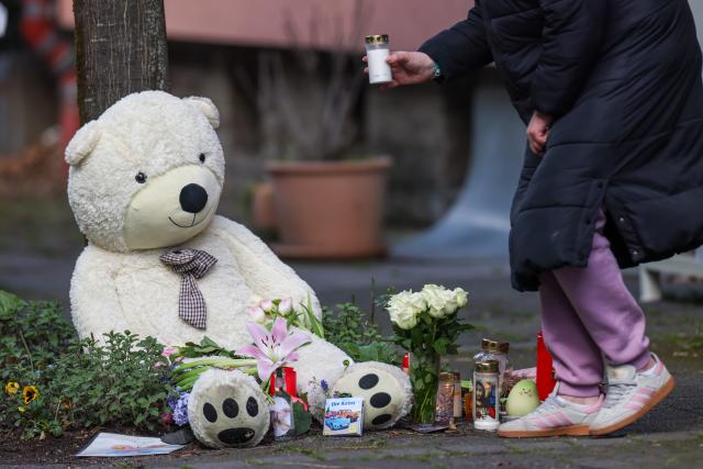 29 March 2026, North Rhine-Westphalia, Witten: A woman places a candle in front of the knife attack victims' home in memory of the 13-year-old boy who died, his mother, who suffered life-threatening injuries, and his sister, who was also critically injured. Photo: Christoph Reichwein/dpa