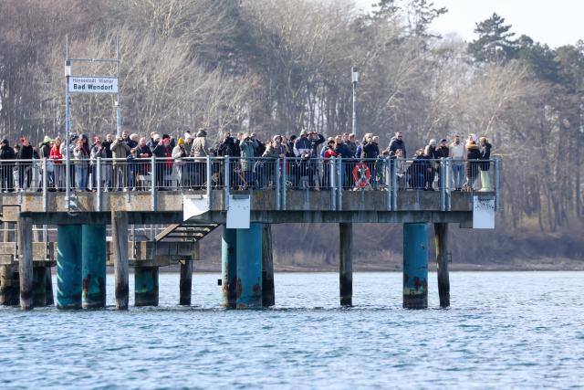 29 March 2026, Mecklenburg-Western Pomerania, Wismar: People gathered on the pier to watch humpback whale in the Bay of Wismar. The humpback whale, which had been freed off Timmendorfer Strand, has stranded again on a sandbar in Wismar Bay. Photo: Bodo Marks/dpa