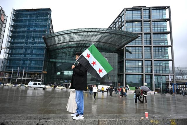 30 March 2026, Berlin: A participant holds up a Syrian flag during a pro-Syrian rally on Washington square in conjunction with Syria's interim president Ahmed al-Sharaa visit to Berlin. Photo: Elisa Schu/dpa