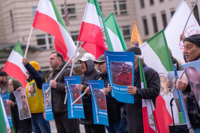 31 March 2026, Berlin: Participants in a rally titled 'Stop the Massacre of Political Prisoners in Iran' hold flags and signs in front of the Brandenburg Gate, protesting the execution of political prisoners in Iran. Photo: Christophe Gateau/dpa
