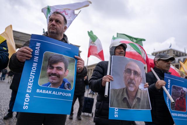 31 March 2026, Berlin: Participants in a rally titled 'Stop the Massacre of Political Prisoners in Iran' hold flags and signs in front of the Brandenburg Gate, protesting the execution of political prisoners in Iran. Photo: Christophe Gateau/dpa