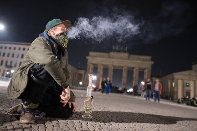 FILED - 31 March 2024, Berlin: A man smokes a bong during a "Smoke In" in front of the Brandenburg Gate. Photo: Sebastian Gollnow/dpa