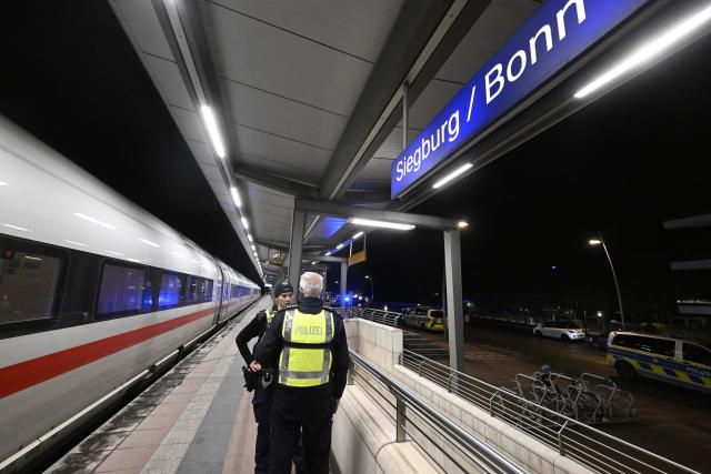 03 April 2026, North Rhine-Westphalia, Siegburg: Police officers stand on a platform at Siegburg Station, where a Deutsche Bahn ICE train is parked. According to the Federal Police, a man threatened to carry out an attack on an ICE train in North Rhine-Westphalia and slightly injured several people. Photo: Roberto Pfeil/dpa
