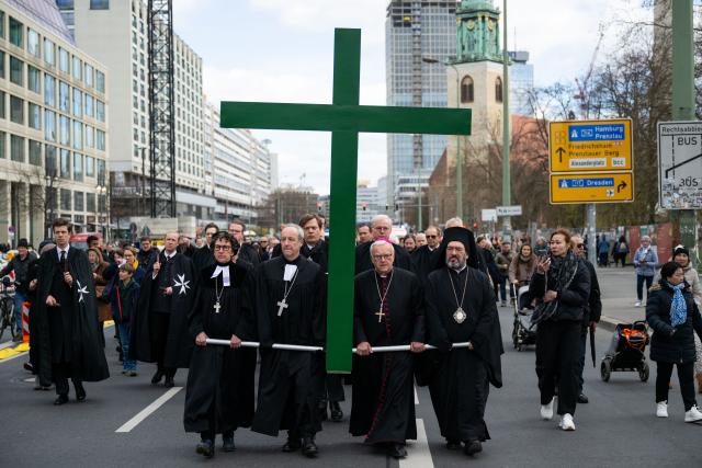 03 April 2026, Berlin: Representatives walk in front of St. Mary's Church carrying a cross during an ecumenical Good Friday procession. The theme of this year's Berlin Good Friday procession is "When the Soul Suffers". Photo: Christophe Gateau/dpa