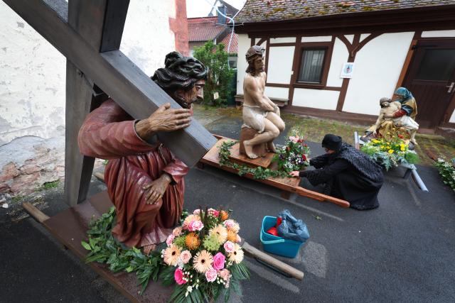 03 April 2026, Bavaria, Lohr am Main: A volunteer is decorating figures depicting religious scenes in the courtyard of St. Joseph's Monastery Church ahead of the Good Friday procession. Photo: Karl-Josef Hildenbrand/dpa