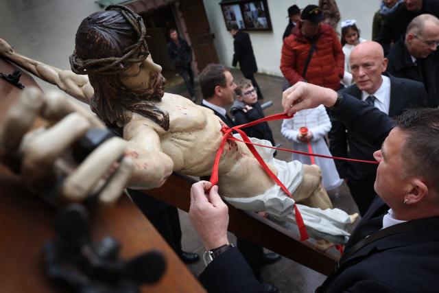 03 April 2026, Bavaria, Lohr am Main: Members of various craft guilds attach ribbons to the wounds of a statue of Jesus before the Good Friday procession. Photo: Karl-Josef Hildenbrand/dpa