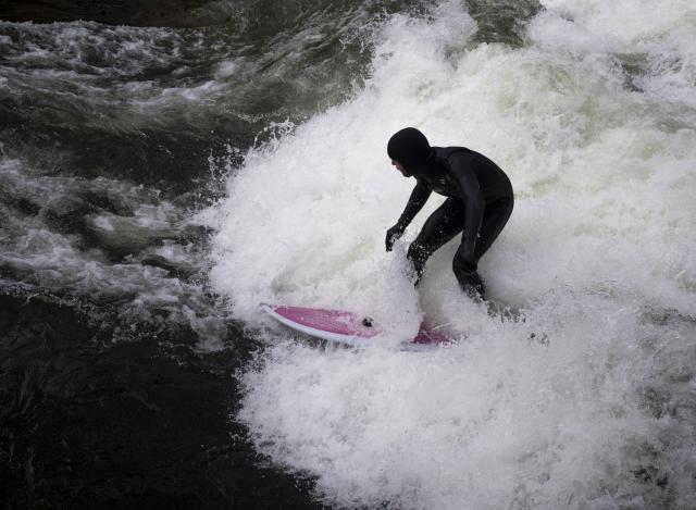 03 April 2026, Bavaria, Munich: A man is surfing on his board on the makeshift Eisbach wave in the English Garden. Photo: Peter Kneffel/dpa