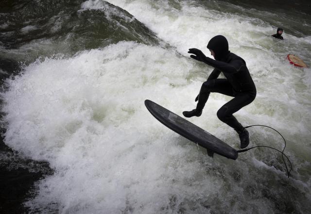 03 April 2026, Bavaria, Munich: A man is surfing on his board on the makeshift Eisbach wave in the English Garden. Photo: Peter Kneffel/dpa