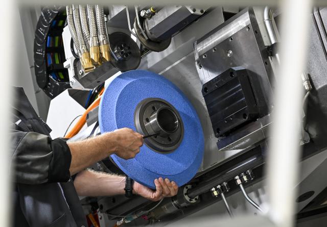 FILED - 29 August 2024, Berlin: A grinding wheel is being mounted in a gear profile grinding machine at KAPP NILES GmbH & Co. KG's Berlin plant. Photo: Jens Kalaene/dpa