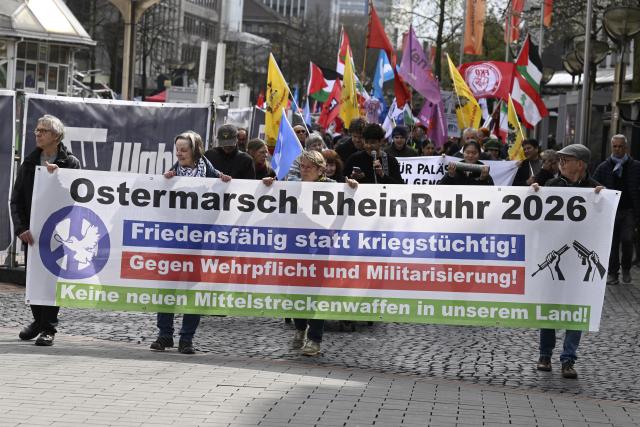 04 April 2026, North Rhine-Westphalia, Duisburg: Participants at the start of the traditional Rhine-Ruhr Easter March walk behind a banner reading "Rhine-Ruhr Easter March 2026 - Capable of peace, not war! - Against conscription and militarization - No new medium-range weapons in our country!". Photo: Roberto Pfeil/dpa