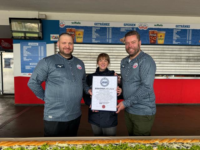 HANDOUT - 04 April 2026, Mecklenburg-Western Pomerania, Rostock: Record-holding judge Laura Koblischek (C) presents the certificate to catering team managing director Christoph Wulff (R) and head chef Jens Schaumburg (L) after producing the world's longest fish sandwich at the Ostseestadion Rostock. Photo: -/F.C. Hansa Rostock/dpa - ACHTUNG: Nur zur redaktionellen Verwendung im Zusammenhang mit der aktuellen Berichterstattung und nur mit vollständiger Nennung des vorstehenden Credits