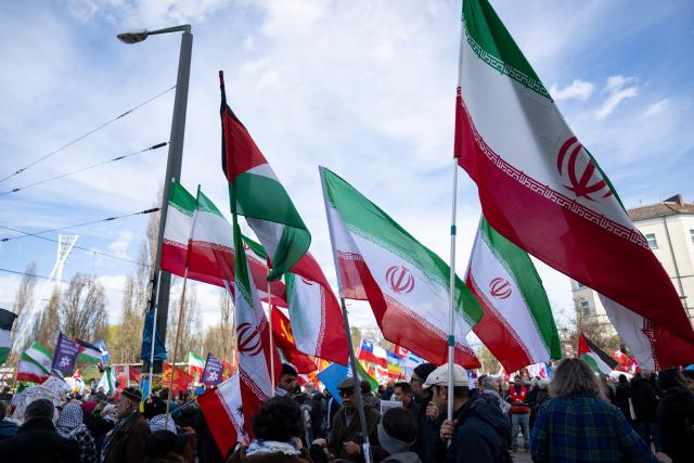04 April 2026, Berlin: Participants hold Iranian flags during the "Demonstration for Peace" Easter March. Photo: Christophe Gateau/dpa