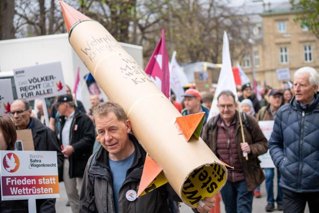 04 April 2026, Baden-Wuerttemberg, Stuttgart: A man carries a cardboard rocket during an Easter march at Schlossplatz under the slogan "Peace-loving instead of 'war-ready'!". Photo: Enrique Kaczor/dpa