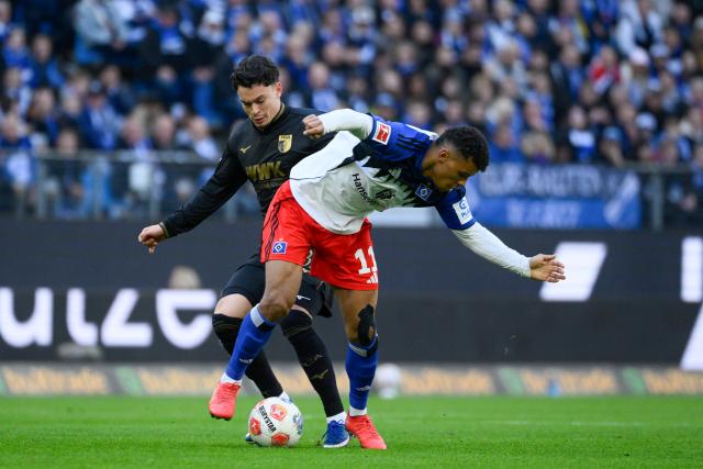 04 April 2026, Hamburg: Hamburger's Ransford Koenigsdoerffer (R) and Augsburg's Fabian Rieder battle for the ball during the German Bundesliga soccer match between Hamburger SV and FC Augsburg at Volksparkstadion. Photo: Gregor Fischer/dpa - WICHTIGER HINWEIS: Gemäß den Vorgaben der DFL Deutsche Fußball Liga bzw. des DFB Deutscher Fußball-Bund ist es untersagt, in dem Stadion und/oder vom Spiel angefertigte Fotoaufnahmen in Form von Sequenzbildern und/oder videoähnlichen Fotostrecken zu verwerten bzw. verwerten zu lassen.