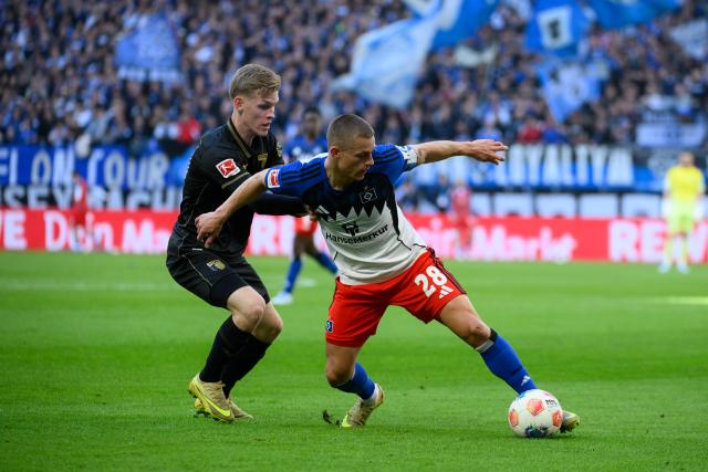 04 April 2026, Hamburg: Augsburg's Anton Kade and Hamburger's Miro Muheim battle for the ball during the German Bundesliga soccer match between Hamburger SV and FC Augsburg at Volksparkstadion. Photo: Gregor Fischer/dpa - IMPORTANT NOTICE: DFL and DFB regulations prohibit any use of photographs as image sequences and/or quasi-video.