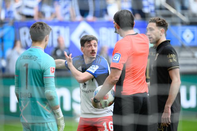 04 April 2026, Hamburg: Hamburger's Giorgi Gocholeishvili talks to referee Deniz Aytekin during the German Bundesliga soccer match between Hamburger SV and FC Augsburg at Volksparkstadion. Photo: Gregor Fischer/dpa - IMPORTANT NOTICE: DFL and DFB regulations prohibit any use of photographs as image sequences and/or quasi-video.