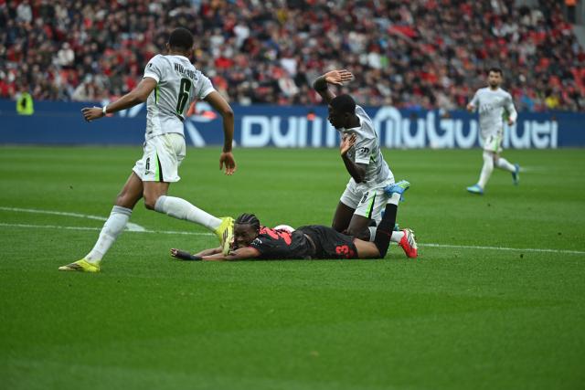 04 April 2026, North Rhine-Westphalia, Leverkusen: Leverkusen's Nathan Tella (C) is fouled by Wolfsburg's Sael Kumbedi during the German Bundesliga soccer match between Bayer Leverkusen and VfL Wolfsburg at BayArena. Photo: Fabian Strauch/dpa - IMPORTANT NOTICE: DFL and DFB regulations prohibit any use of photographs as image sequences and/or quasi-video.
