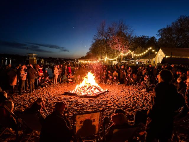 04 April 2026, Berlin: Visitors sit around the Easter bonfire at the Wendenschloss lido. Photo: Britta Pedersen/dpa