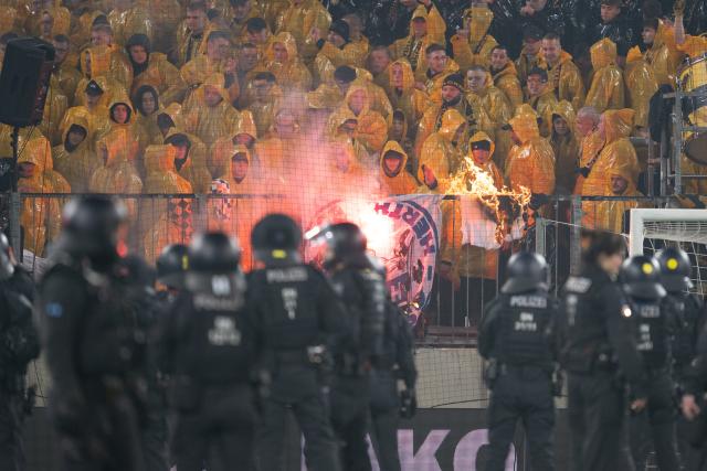 04 April 2026, Saxony, Dresden: Police officers stand in front of the K-Block with Dresden fans during a stoppage at the German 2nd Bundesliga soccer match between Dynamo Dresden and Hertha BSC, at the Rudolf-Harbig-Stadium. Photo: Sebastian Kahnert/dpa - IMPORTANT NOTE: In accordance with the regulations of the DFL German Football League and the DFB German Football Association, it is prohibited to utilize or have utilized photographs taken in the stadium and/or of the match in the form of sequential images and/or video-like photo series.