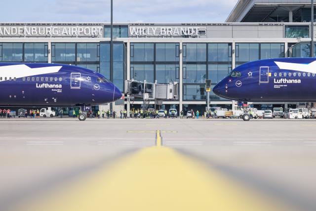 06 April 2026, Brandenburg, Schoenefeld: Two Lufthansa passenger aircraft, a Boeing 787-9 (L) and an Airbus A350-900, are parked nose-to-nose during celebrations marking the 100th anniversary of the first flight at Berlin Brandenburg Airport (BER). Photo: Carsten Koall/dpa