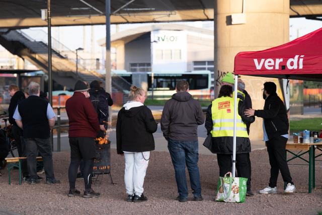 09 April 2026, Saxony, Dresden: Employees of Regionalverkehr Saechsische Schweiz-Osterzgebirge (RVSOE) stand at a picket line next to a fire barrel during a warning strike. The background to the strike is the deadlocked wage negotiations with the local transport employers' association (AVN Group), which, according to Verdi, have still not reached an agreement in the fifth round of negotiations. Photo: Sebastian Kahnert/dpa