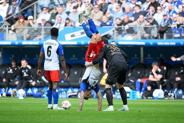 FILED - 04 April 2026, Hamburg: (L-R) Hamburger's Luka Vuskovic and Augsburg's Michael Gregoritsch hold each other after a foul during the German Bundesliga soccer match between Hamburger SV and FC Augsburg at Volksparkstadion. Photo: Gregor Fischer/dpa - IMPORTANT NOTICE: DFL and DFB regulations prohibit any use of photographs as image sequences and/or quasi-video.