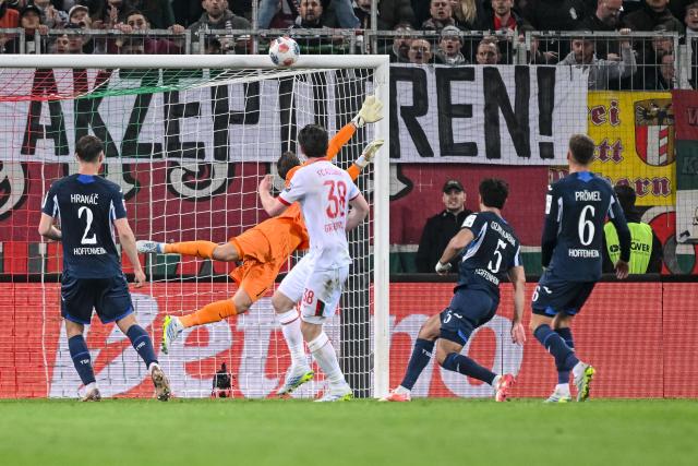 10 April 2026, Bavaria, Augsburg: Augsburg's Michael Gregoritsch (C) hits the crossbar with a shot during the German Bundesliga soccer match between FC Augsburg and TSG 1899 Hoffenheim at the WWK-Arena. Photo: Harry Langer/dpa - WICHTIGER HINWEIS: Gemäß den Vorgaben der DFL Deutsche Fußball Liga bzw. des DFB Deutscher Fußball-Bund ist es untersagt, in dem Stadion und/oder vom Spiel angefertigte Fotoaufnahmen in Form von Sequenzbildern und/oder videoähnlichen Fotostrecken zu verwerten bzw. verwerten zu lassen.