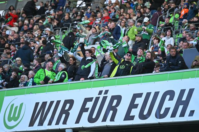 11 April 2026, Lower Saxony, Wolfsburg: VfL Wolfsburg fans hold up scarves during the German Bundesliga soccer match between VfL Wolfsburg and Eintracht Frankfurt at the Volkswagen Arena. Photo: Swen Pförtner/dpa - IMPORTANT NOTICE: DFL and DFB regulations prohibit any use of photographs as image sequences and/or quasi-video.