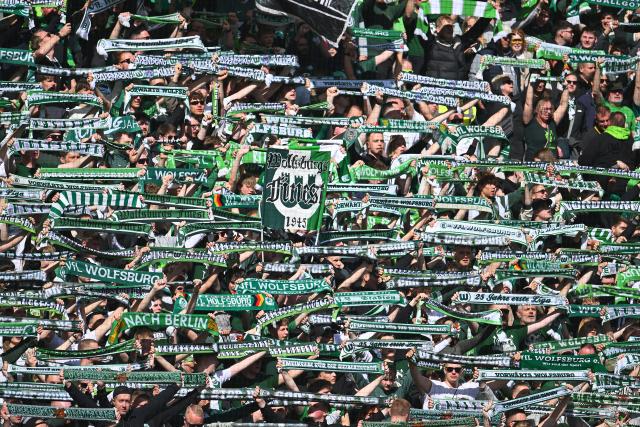 11 April 2026, Lower Saxony, Wolfsburg: Wolfsburg fans hold up scarves in the stands during the German Bundesliga soccer match between VfL Wolfsburg and Eintracht Frankfurt at the Volkswagen Arena. Photo: Swen Pförtner/dpa - IMPORTANT NOTE: In accordance with the regulations of the DFL German Football League and the DFB German Football Association, it is prohibited to utilize or have utilized photographs taken in the stadium and/or of the match in the form of sequential images and/or video-like photo series.