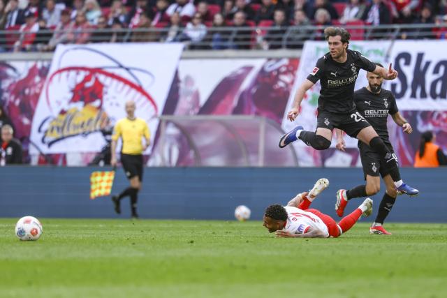 11 April 2026, Saxony, Leipzig: Borussia Moenchengladbach's Joe Scally jumps over RB Leipzig's Antonio Nusa with Borussia Moenchengladbach's Franck Honorat behind him during the German Bundesliga soccer match between RB Leipzig and Borussia Moenchengladbach at Red Bull Arena. Photo: Jan Woitas/dpa - WICHTIGER HINWEIS: Gemäß den Vorgaben der DFL Deutsche Fußball Liga bzw. des DFB Deutscher Fußball-Bund ist es untersagt, in dem Stadion und/oder vom Spiel angefertigte Fotoaufnahmen in Form von Sequenzbildern und/oder videoähnlichen Fotostrecken zu verwerten bzw. verwerten zu lassen.