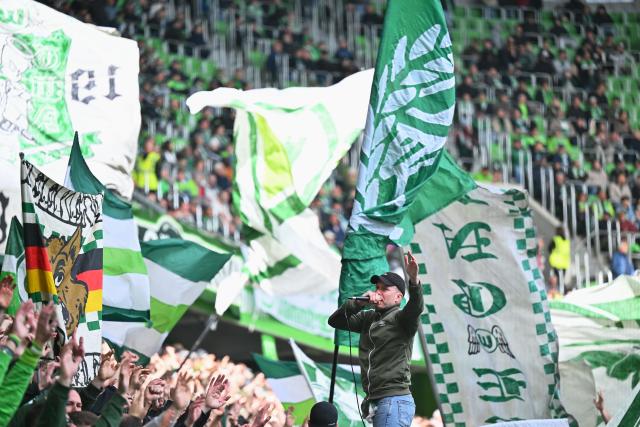 11 April 2026, Lower Saxony, Wolfsburg: Fans wave large flags and cheer from the stands during the German Bundesliga soccer match between VfL Wolfsburg and Eintracht Frankfurt at the Volkswagen Arena. Photo: Swen Pförtner/dpa - IMPORTANT NOTICE: DFL and DFB regulations prohibit any use of photographs as image sequences and/or quasi-video.