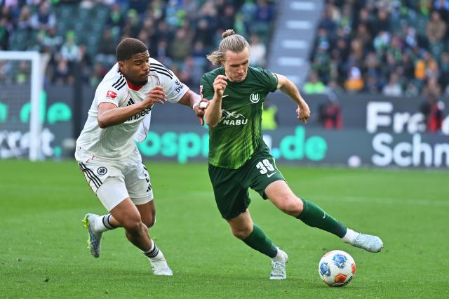 11 April 2026, Lower Saxony, Wolfsburg: Wolfsburg's Patrick Wimmer (R) and Eintracht Frankfurt's Aurele Amenda (L) battle for the ball during the German Bundesliga soccer match between VfL Wolfsburg and Eintracht Frankfurt at the Volkswagen Arena. Photo: Swen Pförtner/dpa - IMPORTANT NOTICE: DFL and DFB regulations prohibit any use of photographs as image sequences and/or quasi-video.