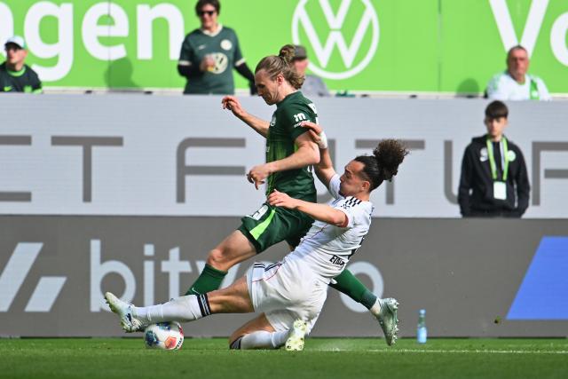 11 April 2026, Lower Saxony, Wolfsburg: Wolfsburg's Patrick Wimmer (L) and Eintracht Frankfurt's Arthur Theate (R) battle for the ball during the German Bundesliga soccer match between VfL Wolfsburg and Eintracht Frankfurt at the Volkswagen Arena. Photo: Swen Pförtner/dpa - IMPORTANT NOTICE: DFL and DFB regulations prohibit any use of photographs as image sequences and/or quasi-video.